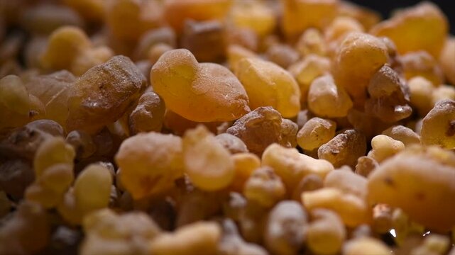 Olibanum Frankincense resin backdrop, Boswellia sacra background. Frankincense or olibanum aromatic resin for incense and perfumes, dark rotating backdrop, design, religion