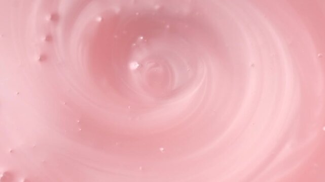 Pearlescent pink liquid soap, shower gel swirl texture, surface of liquid fluid, background, shampoo texture, body care cosmetic, texture of liquid washing gel, soap backdrop top view, rotating. 