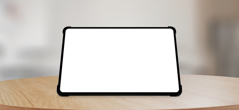 Front view of a tablet mockup resting on a wooden desk with a blurred room background