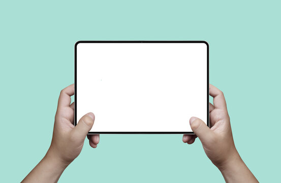 Hands holding a digital tablet with blank white screen mockup on a pastel mint background