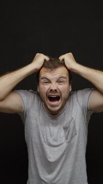 Stressed man screaming and pulling his hair, expressing extreme frustration, panic, anxiety, emotional stress and mental pressure.