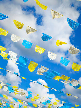 View of colorful papel picado flags hanging against a bright blue sky in Izamal, Yucatan, Mexico.