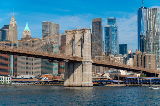 Brooklyn bridge and Manhattan skyline reflected over East river. Brooklyn Bridge tower, suspension cables, Manhattan skyscrapers and small boat on East River