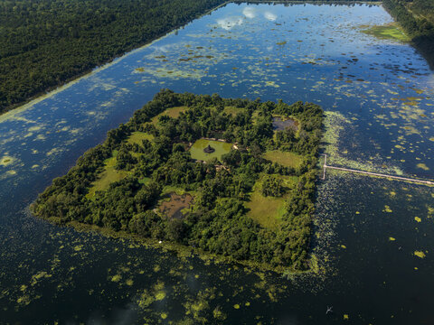 Aerial view of Neak Poan Temple situated on an island in the middle of a large reservoir surrounded by lush forest in Krong Siem Reap, Siem Reap Province, Cambodia.