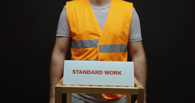 Industrial worker presenting a &ldquo;Standard Work&rdquo; sign, representing standardized procedures, lean manufacturing, process consistency and operational efficiency.