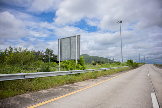 Highway roadside blank billboard sky cloud landscape empty road beside guardrail and blank roadside billboard cloudy blue sky, green vegetation and distant hill, calm travel and transportation