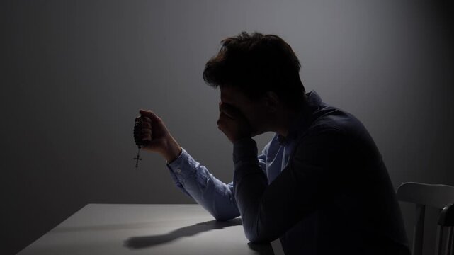 Man finding solace and spiritual guidance, holding a rosary while praying in a moment of reflection and deep contemplation, seeking comfort during difficult times