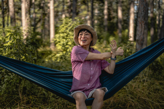Woman enjoying nature while stretching in forest hammock