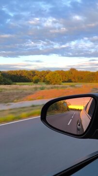 Reflection of a bright sunset in the side mirror of a moving car.