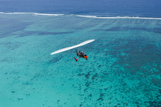 Aerial view of a microlight aircraft flying over the turquoise waters and coral reef of the Ningaloo Coast in Ningaloo, Western Australia, Australia.