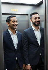 Fototapeta premium Two smiling diverse businessmen in suits riding an elevator, corporate environment and professional success concept, the men appear happy and confident