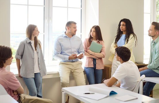 Teacher and students in classroom discussion. A professor leads a talk as a diverse group listening, useful for education, higher ed training and onboarding. Clear concept of team learning.