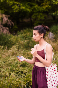 Young woman smoking cannabis joint outdoors in nature