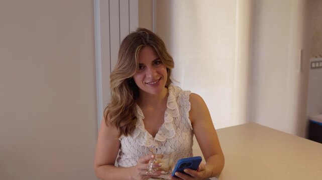 Smiling beautiful woman using smartphone at home