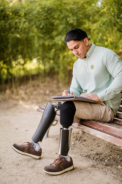 Latino man with prosthetic legs writing outdoors
