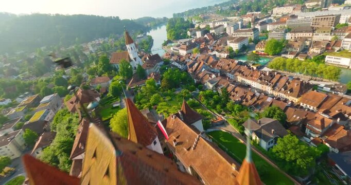 FPV aerial view of Thun Castle surrounded by historic town buildings and lush greenery in Switzerland.