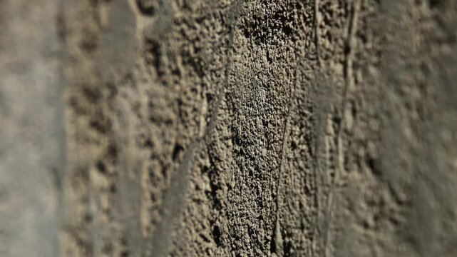 Slow horizontal camera pan from right to left showcasing the intricate details, roughness, and natural texture of a rugged stone surface.