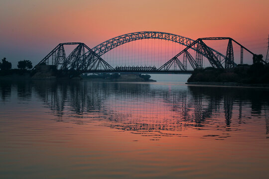 FPV aerial view of Ayub Bridge over the Indus River at sunset in Sukkur, Sindh, Pakistan.