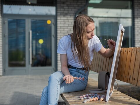 A Caucasian woman with mild cerebral palsy paints by numbers outdoors