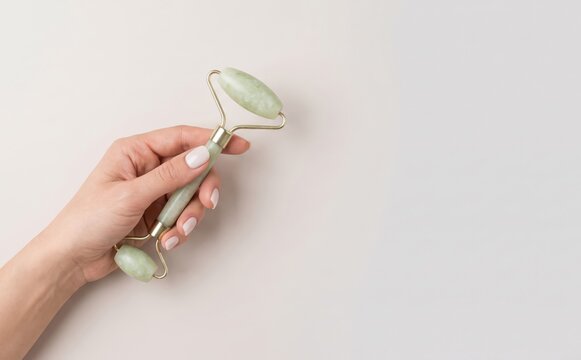 Woman holding a green jade facial roller for skin care massage and anti aging beauty treatment