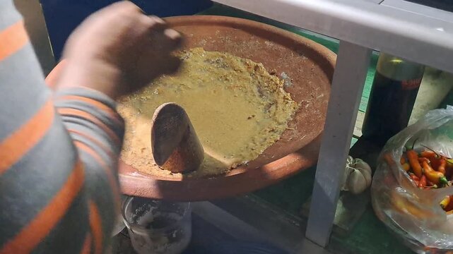 Street food vendor preparing Tahu Tek, a traditional East Javanese dish. Close up of cutting fried tofu, omelet, rice cakes using scissors, mixing rich peanut sauce. SUMENEP, INDONESIA - MAY 27, 2026