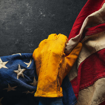 Worn work glove pulling back the American flag. Symbolic of blue collar workers, USA manufacturing, pride in products Made in United States of America, or to celebrate Father's day or US Labor Day.