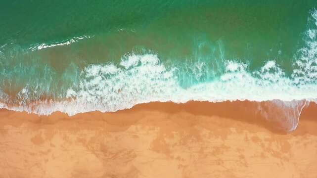Top down drone perspective of Atlantic surf breaking across an empty sandy beach on the Portuguese coast.