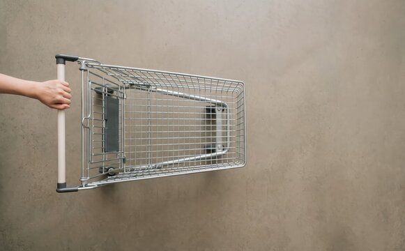 Top view of a person pushing an empty shopping cart on a concrete floor representing retail and grocery shopping concepts