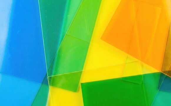 Colorful transparent plastic sheets overlap to create vibrant abstract geometric patterns and backgrounds