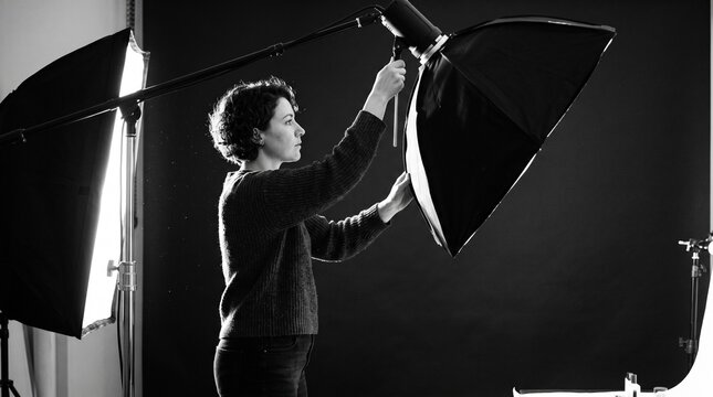 Photographer adjusting studio lighting equipment for a photoshoot