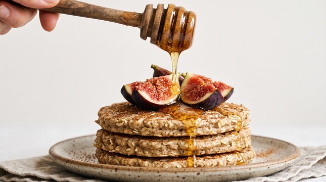 Stack of healthy oat pancakes drizzled with honey and topped with fresh figs