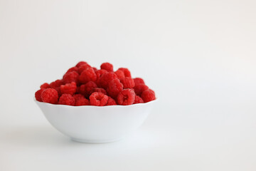 A close‑up of a red raspberry on a white background. © Мария Чепрасова