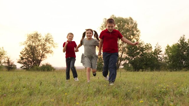 Sunset fun for kids, Running through the grass, Young friends holding hands, Girls and boys playing outside, Warm evening with children, Childhood memories, Cheerful group of kids, Green field with