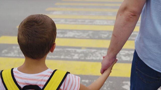 Back to school safety, Parent and child walking, Boy with backpack crossing street, Safe pedestrian behavior, Child learning road safety, Crossing the road with dad, Family moment outdoors, Holding