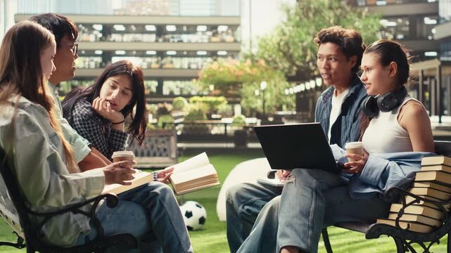 Woman student discusses project notes with classmates near an open laptop on a campus bench, supporting peer tutoring and collaborative academic teamwork.