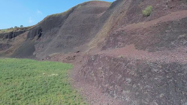 Aerial volcanic tuff cone layers reveal exposed mineral bands and rugged geologic structure.