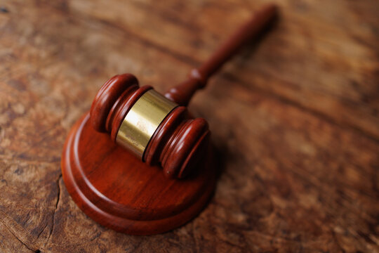 Gavel representing law, justice, and authority, resting on a rustic wooden table in a legal context