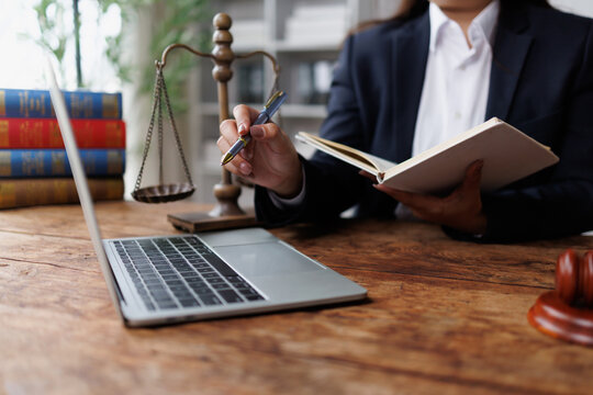 Lawyer working on legal research and planning with laptop, scales of justice, and law books in office