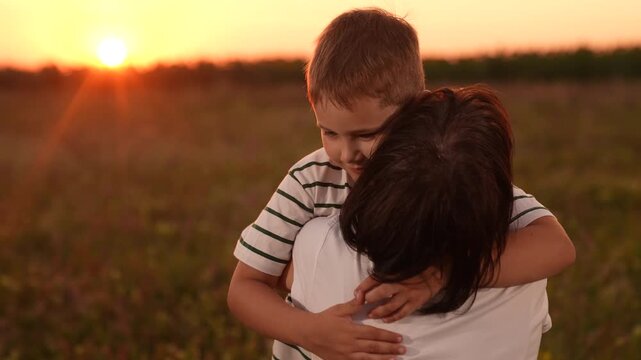 Mother son reunion sunset, Happy child running embrace parent, Family love nature dusk, Warm sunset hug meadow, Joyful boy with open arms, Mother waiting child embrace, Golden hour family moment