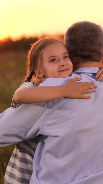Father man hugging happy daughter child sunset, Father and daughter hug at sunset, Close family bond outdoors, Emotional embrace in nature, Loving father and happy child, Warm sunset in the field