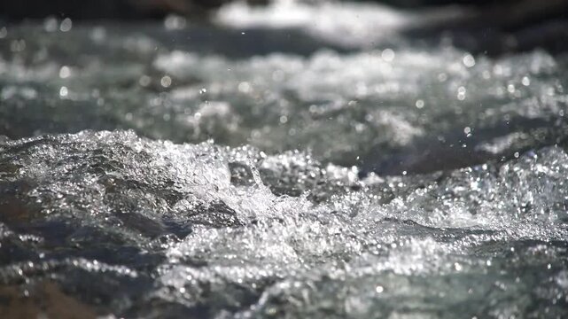 Mountain stream rushes over rocks through alpine terrain with clear fast water and raw energy.