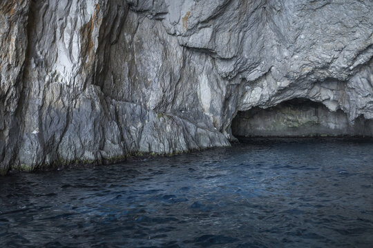View of the rugged limestone rock formations and deep blue sea inside a sea cave in Zakinthos, Greece.