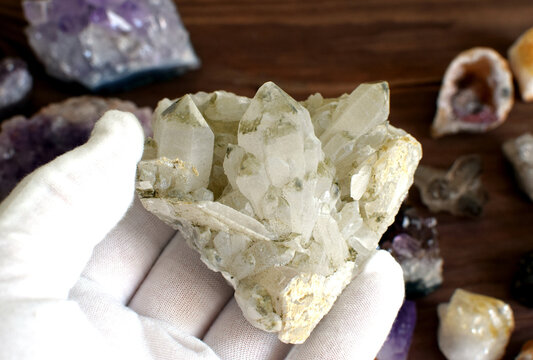 A hand in a white glove holds a quartz crystal stone.