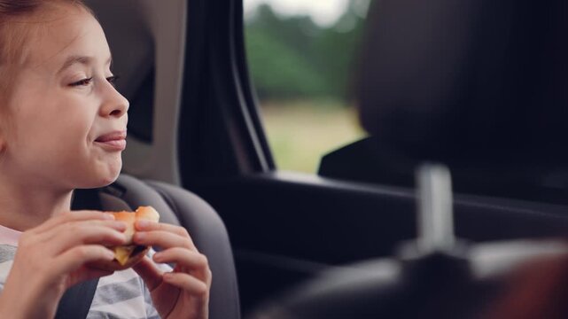 little girl child eating burger in car, happy person, Bite of happiness, child and fast food, lunch on wheels, hungry explorers, quick snack during road trip, tasty sandwich moment, satisfaction in a