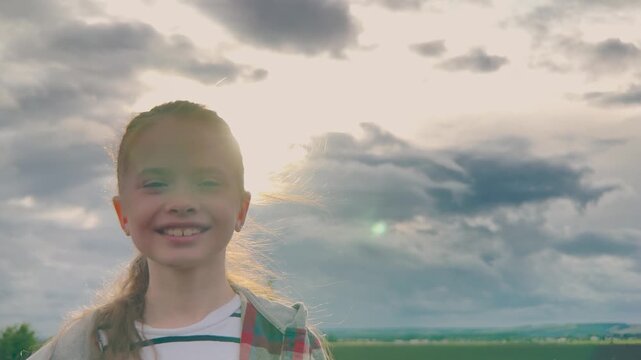 Enthusiastic smile, Little girl in nature, Fresh air and sunshine, Wild hair flying, Pure childhood happiness, Bright outdoor portrait, Cheerful young face, Joy captured, Heartwarming image, Radiant