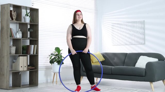 Overweight woman with hula hoop after training at home