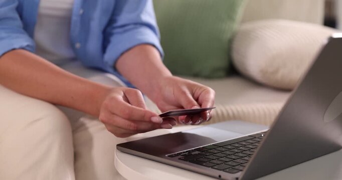 Online store. Woman with credit card using laptop at white table indoors, closeup