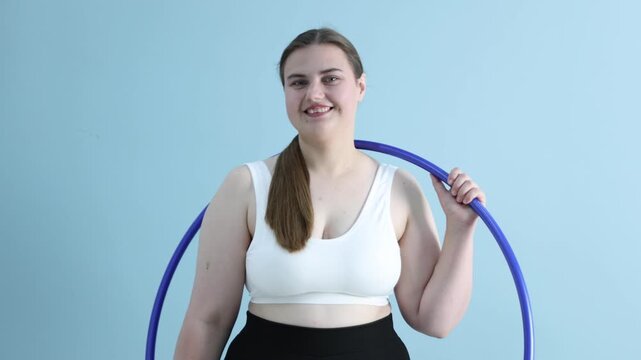 Overweight woman with hula hoop on light blue background