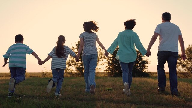 People running towards sunset hand raised up sunset, happy family, woman mother man father child kid boy girl running park, group people playing game, holding hands unity, outdoor recreation family