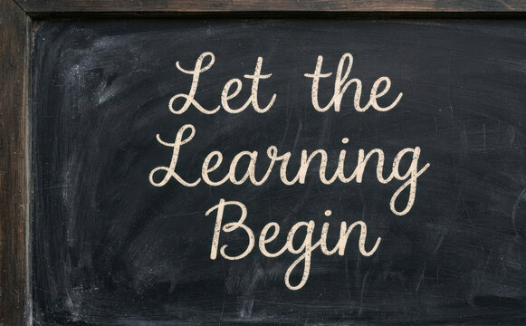 Let the Learning Begin message written in white chalk on a dark black classroom chalkboard for education and school concepts